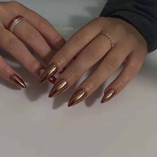 Uñas postizas de aplicación mediante presión de color bronce claro metálico con espejo, uñas tipo stiletto de almendra media con pegamento, uñas